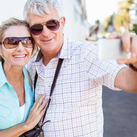Happy tourist couple taking a selfie in the city on a sunny dayの写真素材