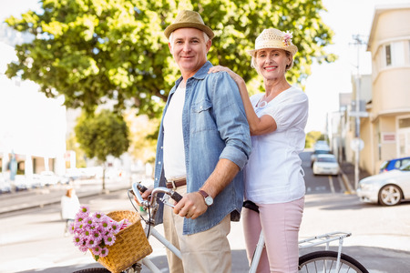 Happy mature couple going for a bike ride in the city on a sunny dayの写真素材