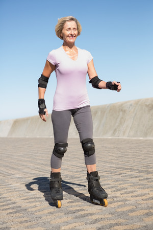 Active senior woman rollerblading on the pier on a sunny dayの写真素材