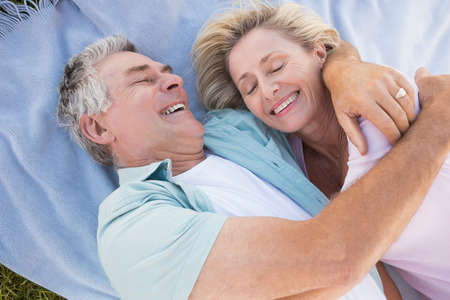 Happy senior couple cuddling on blanket on a sunny dayの写真素材