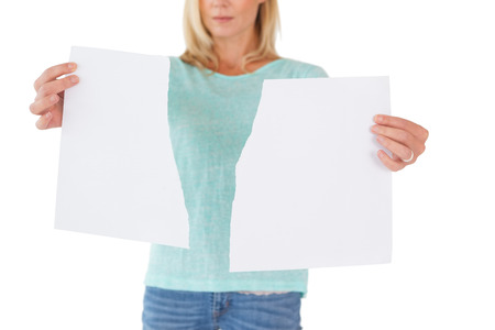 Serious woman holding torn sheet of paper on white backgroundの写真素材