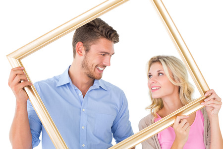 Attractive young couple holding picture frame on white backgroundの写真素材