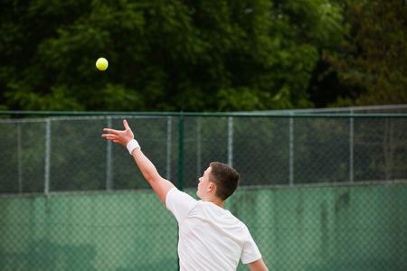 Young tennis player about to serve on a sunny dayの写真素材