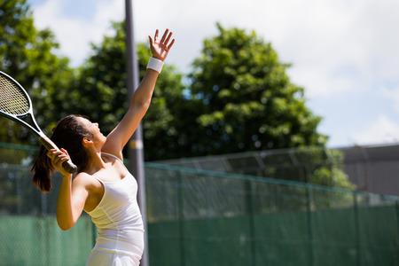 Pretty tennis player about to serve on a sunny dayの写真素材