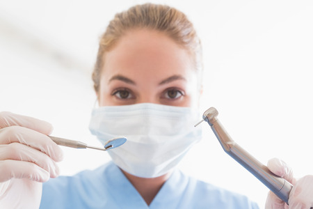 Dentist in surgical mask holding tools over patient at the dental clinicの写真素材