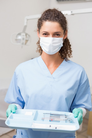 Dentist in blue scrubs holding tray of tools at the dental clinicの写真素材