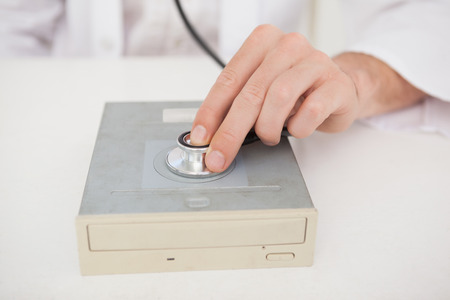 Computer engineer listening to harddrive with stethoscope in his office