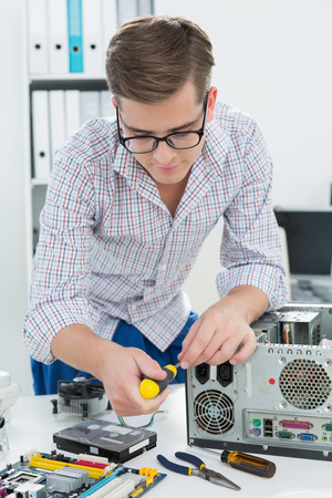 Young technician working on broken computer in his officeの写真素材