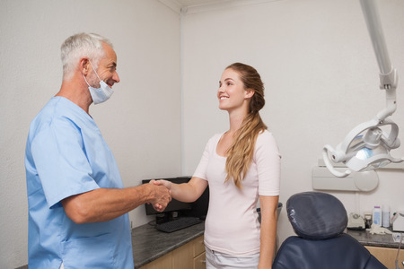 Dentist shaking hands with his patient at the dental clinicの写真素材