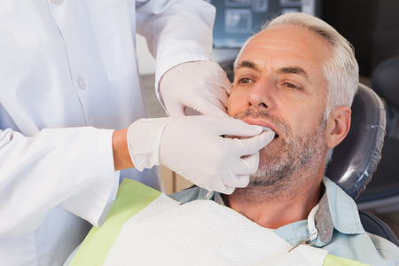 Dentist examining a patients teeth in the dentists chair at the dental clinic