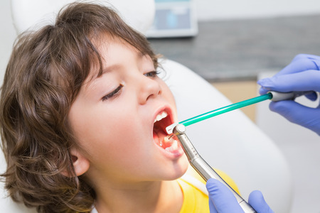 Pediatric dentist examining a little boys teeth in the dentists chair at the dental clinicの写真素材