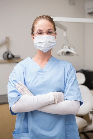 Dentist in blue scrubs smiling at camera at the dental clinicの写真素材