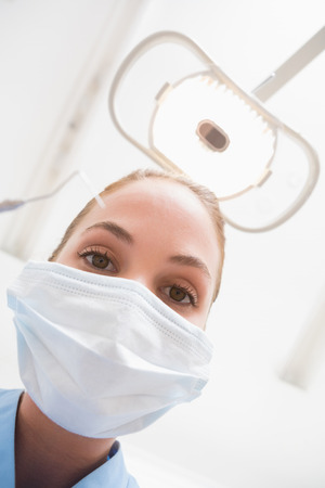 Dentist in surgical mask holding dental explorer over patient at the dental clinicの写真素材