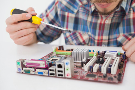 Computer engineer working on cpu with screwdriver in his officeの写真素材