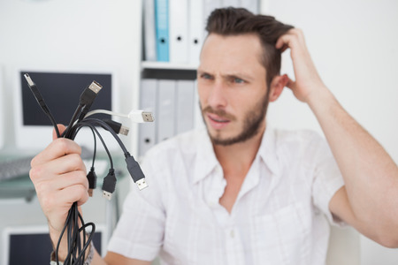 Confused computer engineer looking at wires in his officeの写真素材