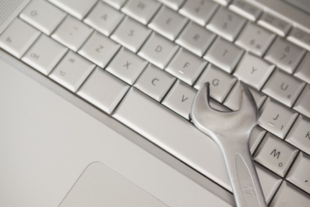 Pliers lying on silver keyboard in officeの写真素材