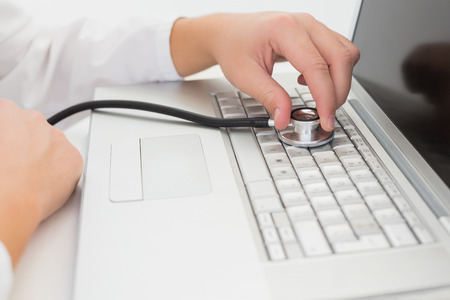Technician listening to laptop with stethoscope in his office