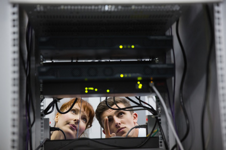 Team of technicians talking and looking at server in large data centerの写真素材