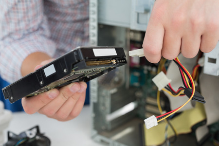 Young technician working on broken computer in his office