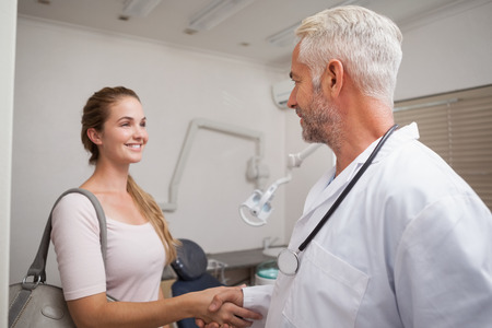 Dentist shaking hands with his patient at the dental clinicの写真素材