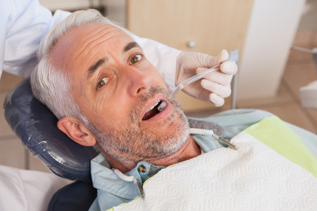 Dentist examining a patients teeth in the dentists chair at the dental clinicの写真素材