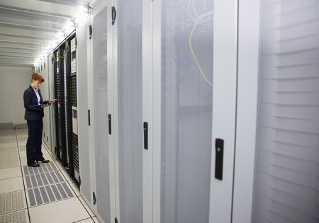 Technician working on servers using tablet pc in large data center