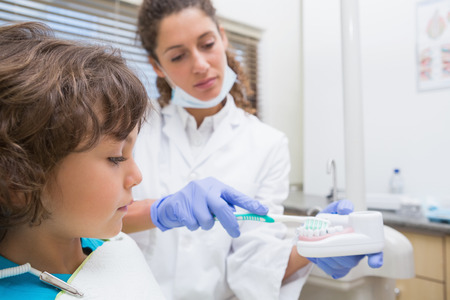 Pediatric dentist showing little boy how to brush his teeth at the dental clinicの写真素材