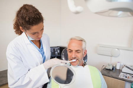 Patient admiring his new smile in the mirror at the dental clinicの写真素材
