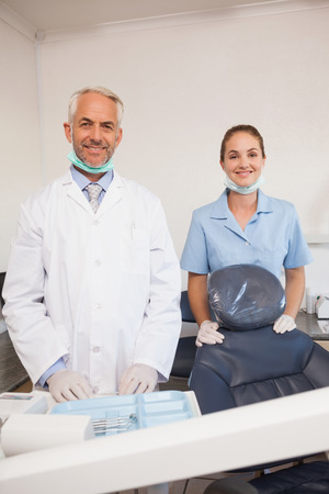 Dentist and assistant smiling at camera at the dental clinicの写真素材