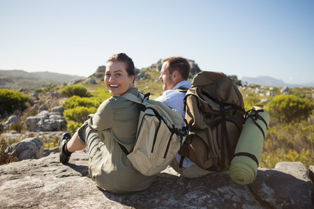 Hiking couple sitting on mountain terrain on a sunny dayの写真素材