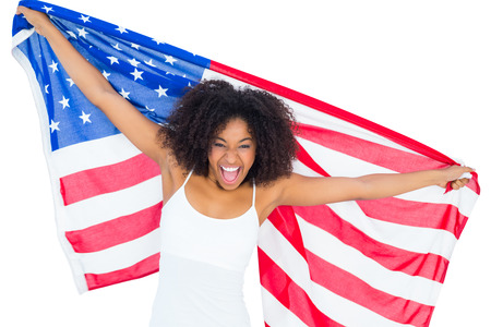 Pretty cheering girl in white top holding american flag on white backgroundの写真素材
