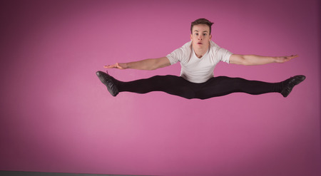 Focused male ballet dancer leaping doing the splits in the dance studio