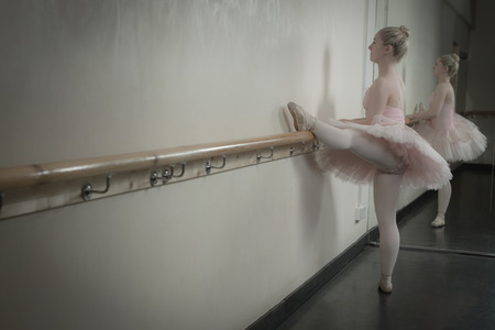 Beautiful ballerina warming up with the barre in the dance studioの写真素材