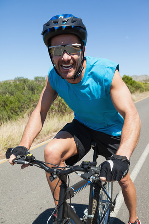 Smiling cyclist riding on the open road on a sunny dayの写真素材