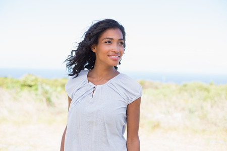 Casual pretty woman standing in the wind on a sunny day in the countryside