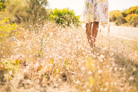 Woman in floral dress standing by the road on a sunny day in the countrysideの写真素材