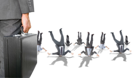 Composite image of businessman holding briefcase with business people hiding heads in groundの写真素材