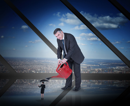 Mature businessman watering tiny business team against room with large window looking on cityの写真素材