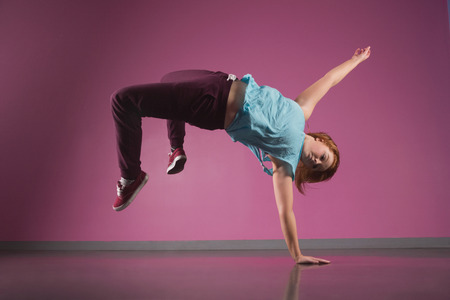 Pretty break dancer doing a handstand in the dance studio