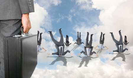 Businessman holding briefcase against blue sky with white clouds and business peopleの写真素材