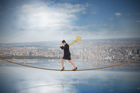 Wound up businesswoman gesturing on tightrope against room with large window looking on cityの写真素材