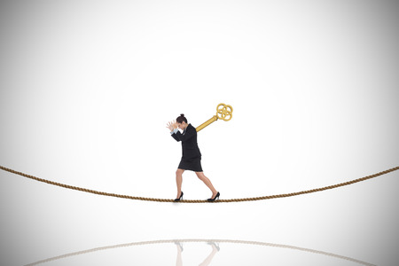 Wound up businesswoman gesturing on tightrope against white background with vignetteの写真素材