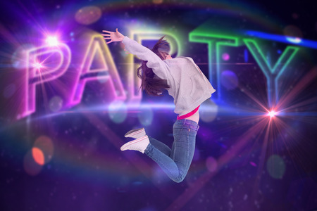 Cheerful young woman jumping against digitally generated colourful party textの写真素材