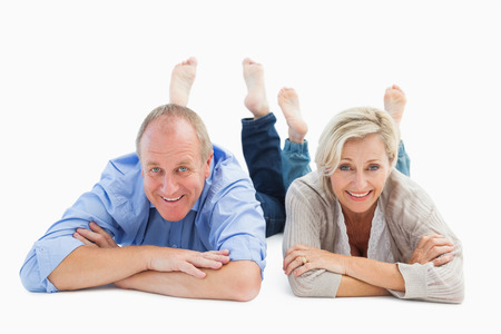 Happy mature couple lying and smiling on white backgroundの写真素材