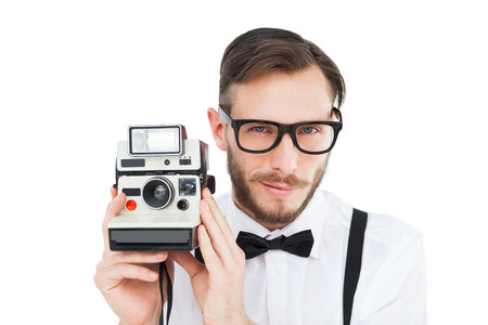 Geeky hipster holding a retro camera on white backgroundの写真素材