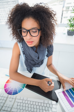 Pretty designer working at her desk in her officeの写真素材