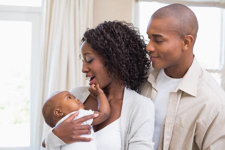 Happy young parents spending time with baby at home in the living roomの写真素材
