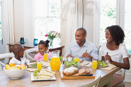 Happy family enjoying a healthy meal together at home in the kitchenの写真素材