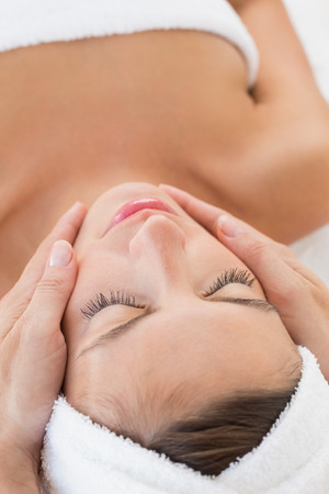 Close up of an attractive young woman receiving facial massage at spa centerの写真素材