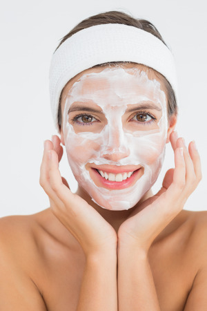 Close-up of an attractive woman having white cream on her face at spa centerの写真素材